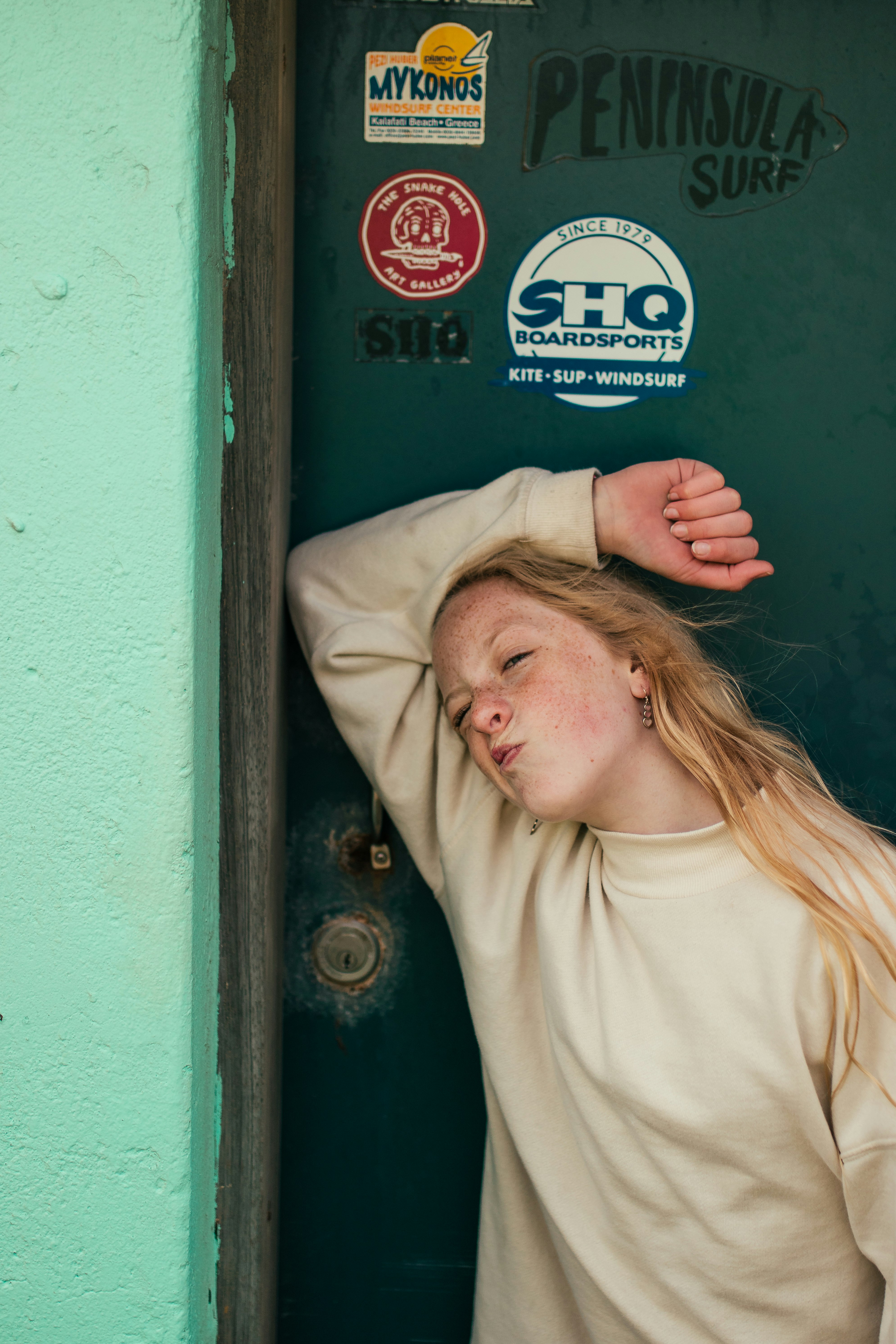 woman in beige crew neck shirt leaning on green wooden door